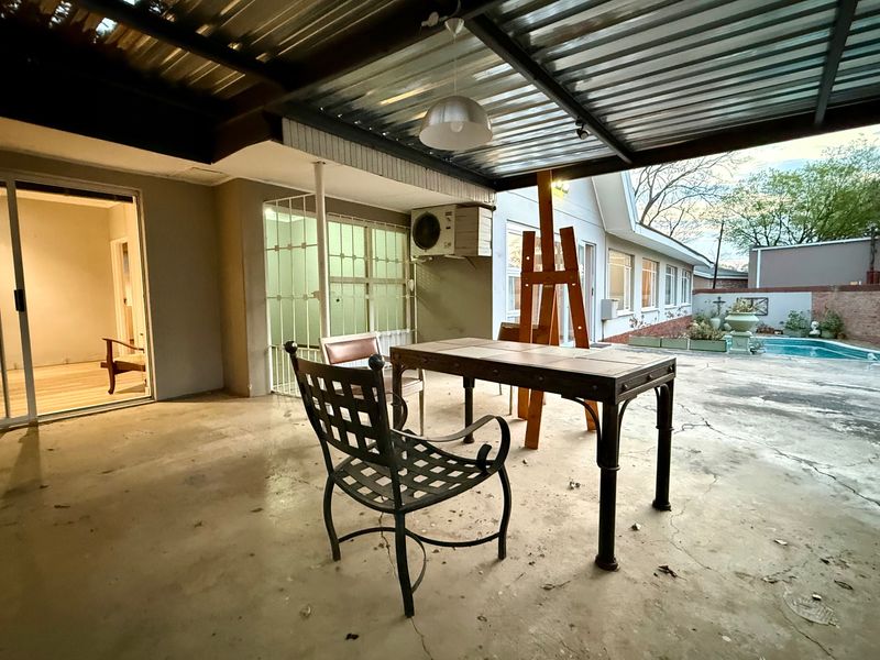 Covered outdoor patio area featuring a corrugated metal roof, concrete flooring, and direct access to the main house through sliding glass doors.