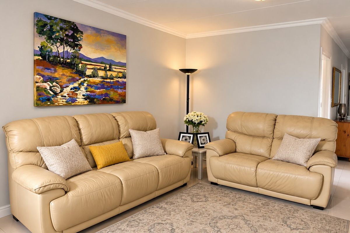 A well-maintained living room featuring neutral tiled flooring, crisp wall finishes, and decorative ceiling cornicing.