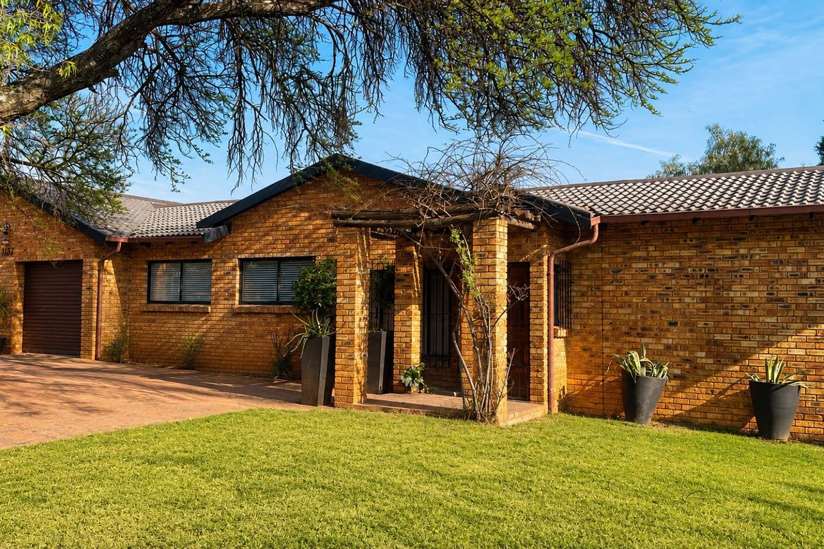 A well-maintained single-story face brick house featuring a double garage, covered entrance porch, and a neat front lawn with paved driveway.