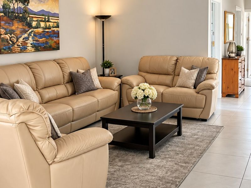 A well-maintained living room featuring neutral tiled flooring, cove cornicing, and a clean, bright layout.