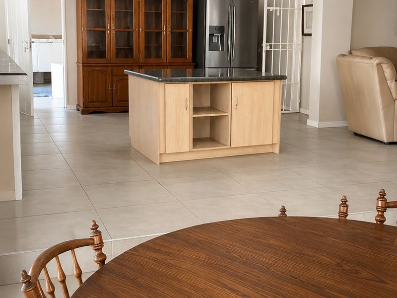 Open plan living area featuring tiled flooring and a central kitchen island, providing a versatile space for dining and relaxation.