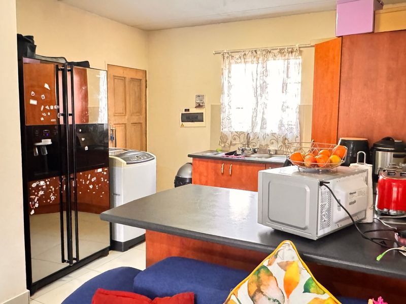 A functional kitchen featuring laminate cabinetry, dark countertops, and a stainless steel sink, offering a practical layout for daily meal preparation.
