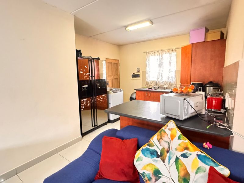 Open-plan living and kitchen area featuring tiled flooring, functional cabinetry, and a breakfast counter, offering a practical layout for daily living.