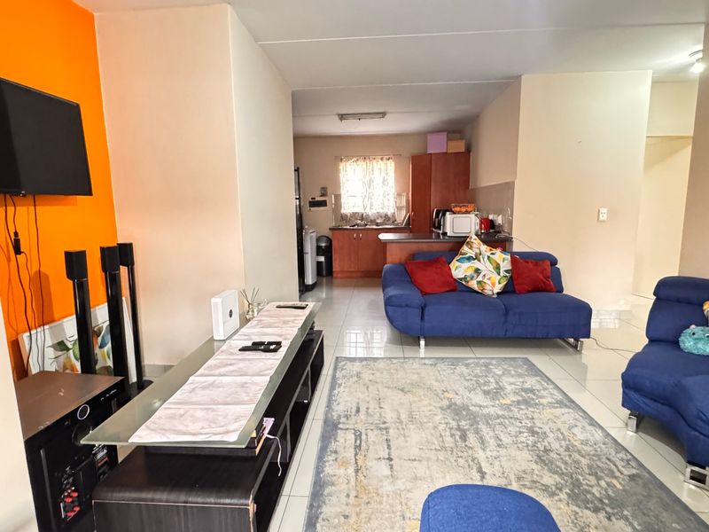 Open-plan living area featuring tiled flooring and a functional kitchen with built-in cabinetry and countertops, creating a combined space for living and dining.