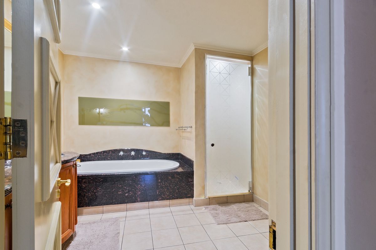 A well-maintained bathroom featuring a built-in bathtub with granite surround, a separate shower with a frosted glass door, and neutral wall finishes.