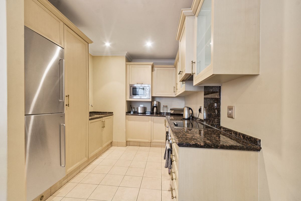 A well-maintained kitchen featuring light wood cabinetry, granite countertops, integrated appliances, and ceramic floor tiles.