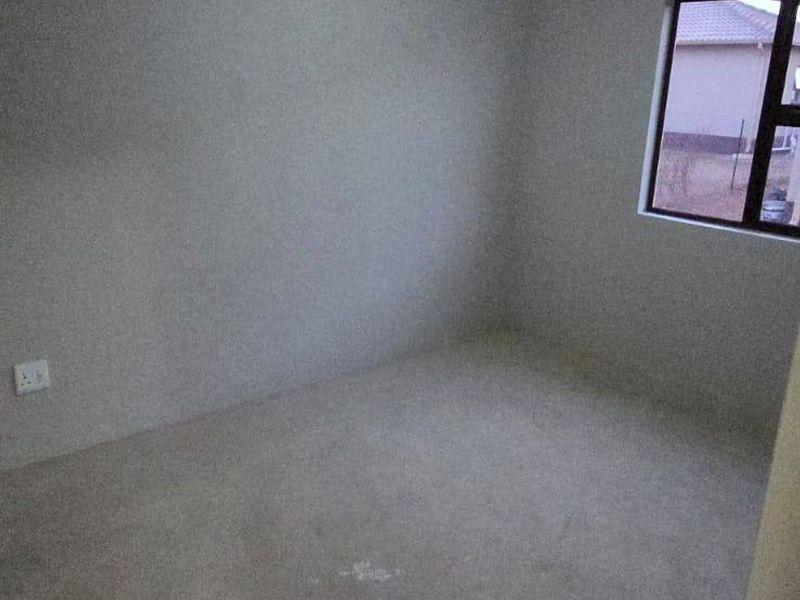 An empty bedroom featuring neutral walls, a window, and carpet flooring, providing a blank canvas for personalization.