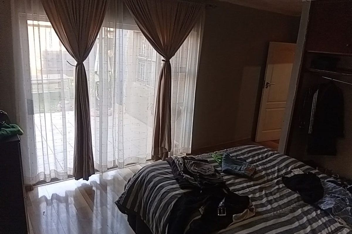 Bedroom featuring laminate flooring, a built-in wardrobe, and a sliding glass door providing access to an outdoor patio area.