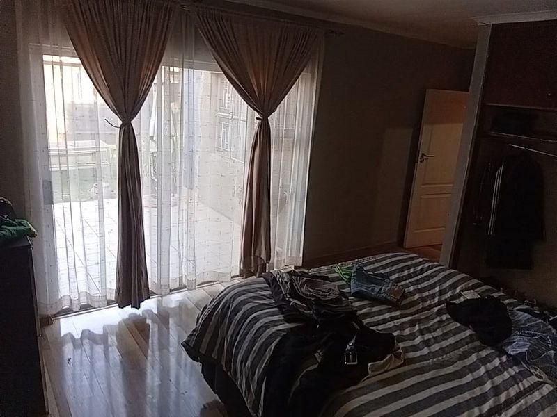 Bedroom featuring laminate flooring, a built-in wardrobe, and a sliding glass door providing access to an outdoor patio area.