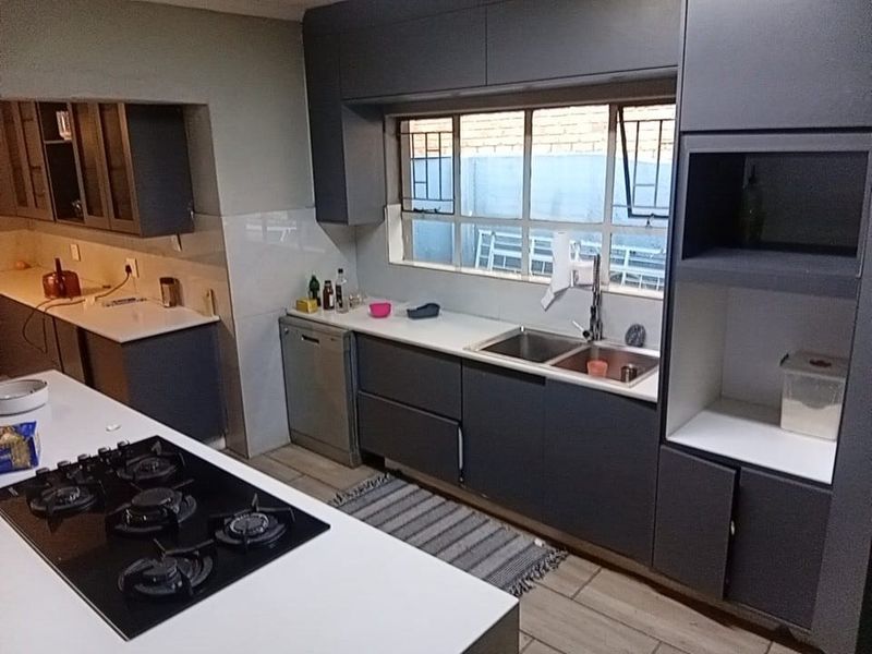 Modern kitchen featuring dark grey cabinetry, stone countertops, a built-in gas hob, and a double sink with a window view.