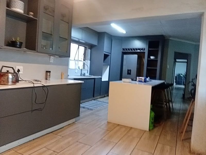 Modern kitchen featuring dark grey cabinetry, a central island with stone countertops, and tiled flooring, offering a functional and contemporary cooking space.