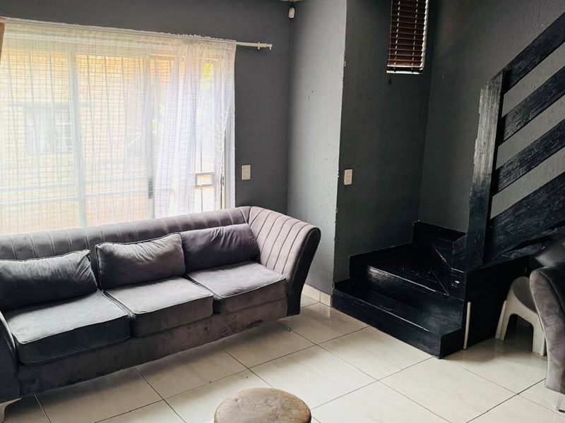 A living room featuring tiled flooring, a staircase with a dark finish, and a sliding glass door providing access to the exterior.