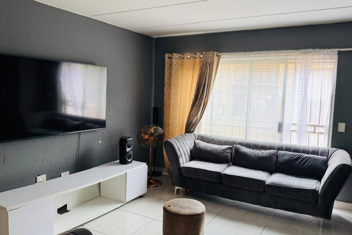 A living room featuring tiled flooring and a sliding glass door providing natural light.