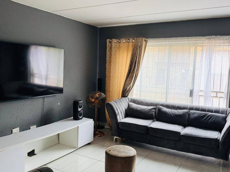 A living room featuring tiled flooring and a sliding glass door providing natural light.