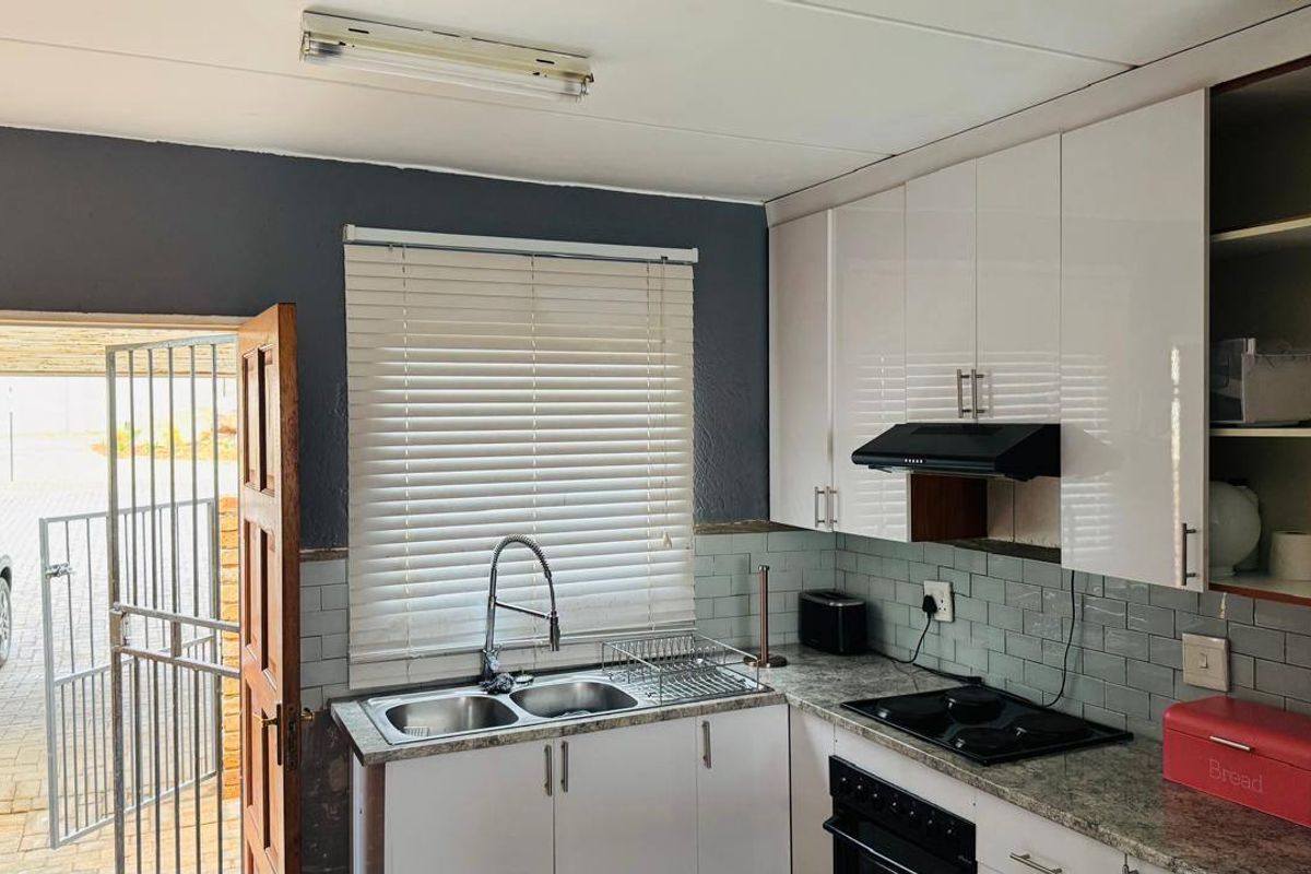 Functional kitchen featuring white cabinetry, subway tile backsplash, granite-look countertops, and integrated appliances, with direct access to the exterior.