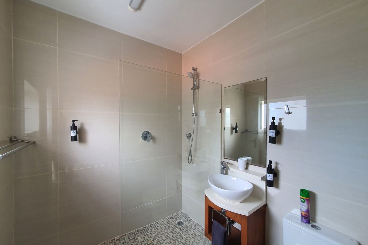 Modern bathroom featuring a glass-enclosed shower with mosaic tiling, a contemporary vessel sink vanity, and a wall-mounted mirror.