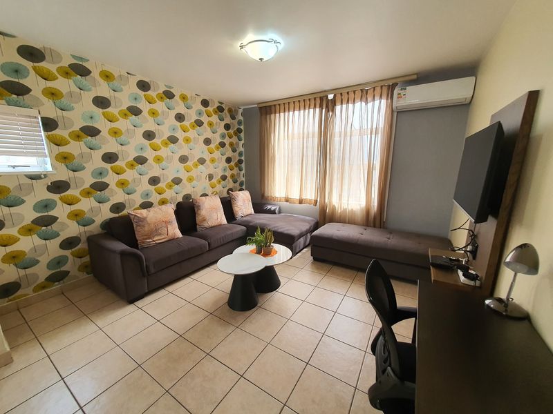 A living room featuring ceramic floor tiles, a wall-mounted split-system air conditioner, and a decorative feature wall.