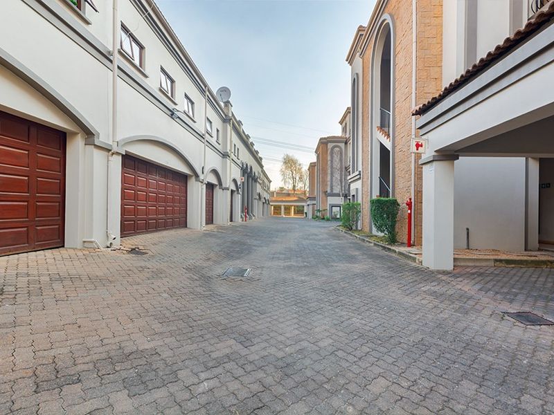 A view of the apartment complex driveway featuring paved surfaces, multiple garage access points, and covered parking bays.