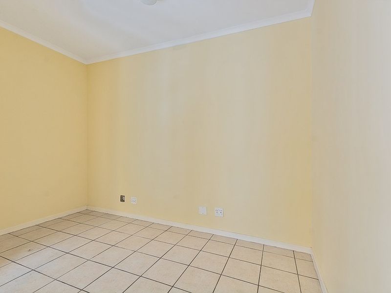 An empty bedroom featuring neutral yellow walls, tiled flooring, and coved ceiling detailing.