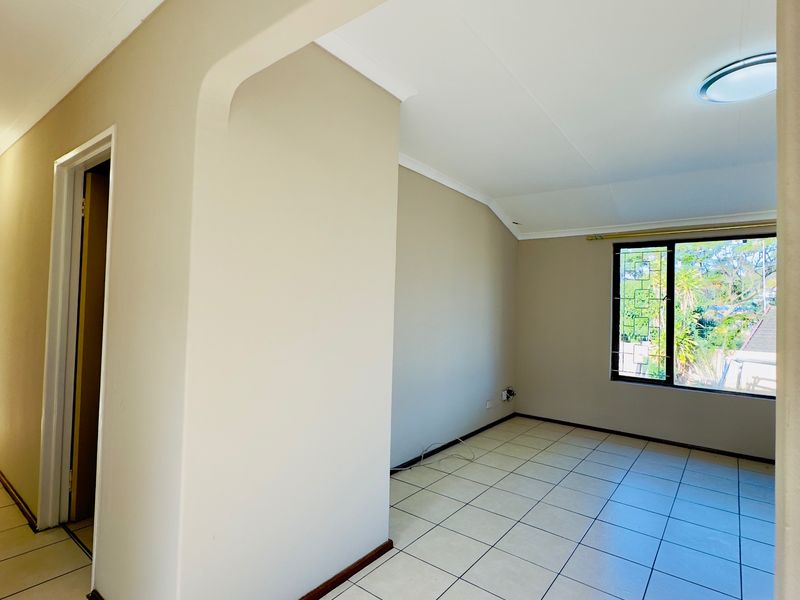 A bright, empty living area featuring neutral tiled flooring, a leaded glass window, and clean wall finishes, ready for personalization.