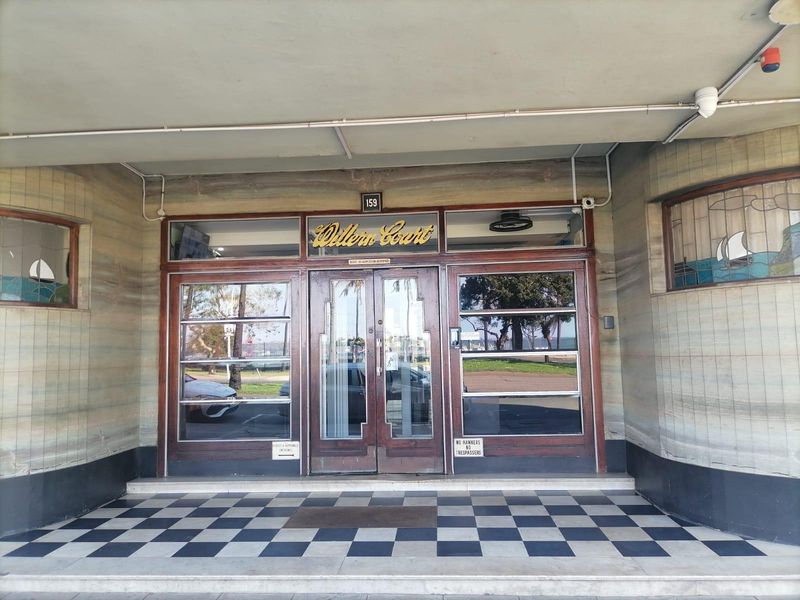 The main entrance of Willern Court features classic timber-framed glass doors, decorative stained glass side panels, and a distinctive checkerboard tiled porch.