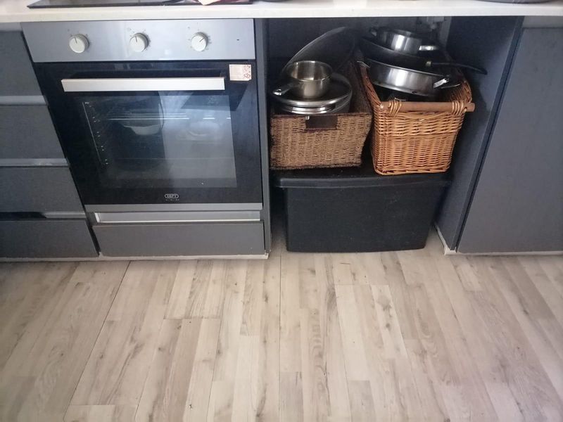 A kitchen section featuring a built-in oven and light-toned laminate flooring, providing a functional cooking space.