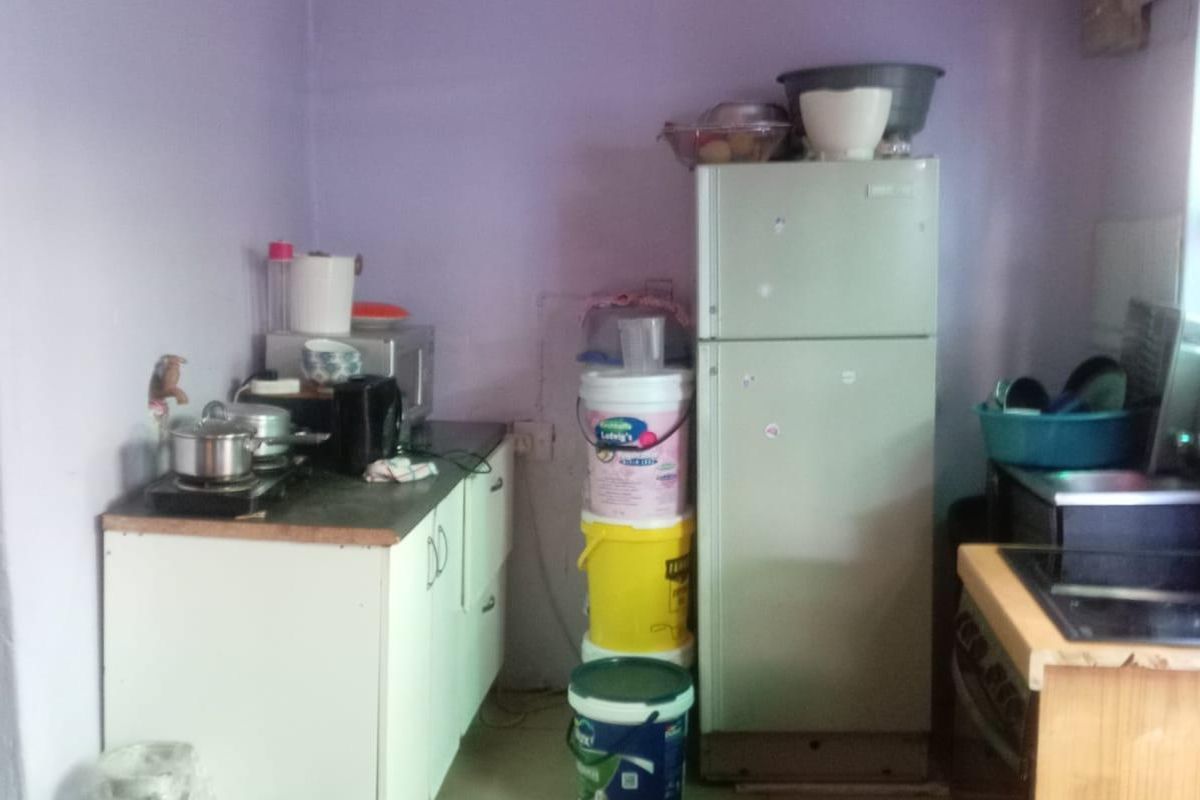 A small, basic kitchen area featuring simple base cabinetry, tiled flooring, and dated wall finishes, requiring significant cosmetic updates and modernization.
