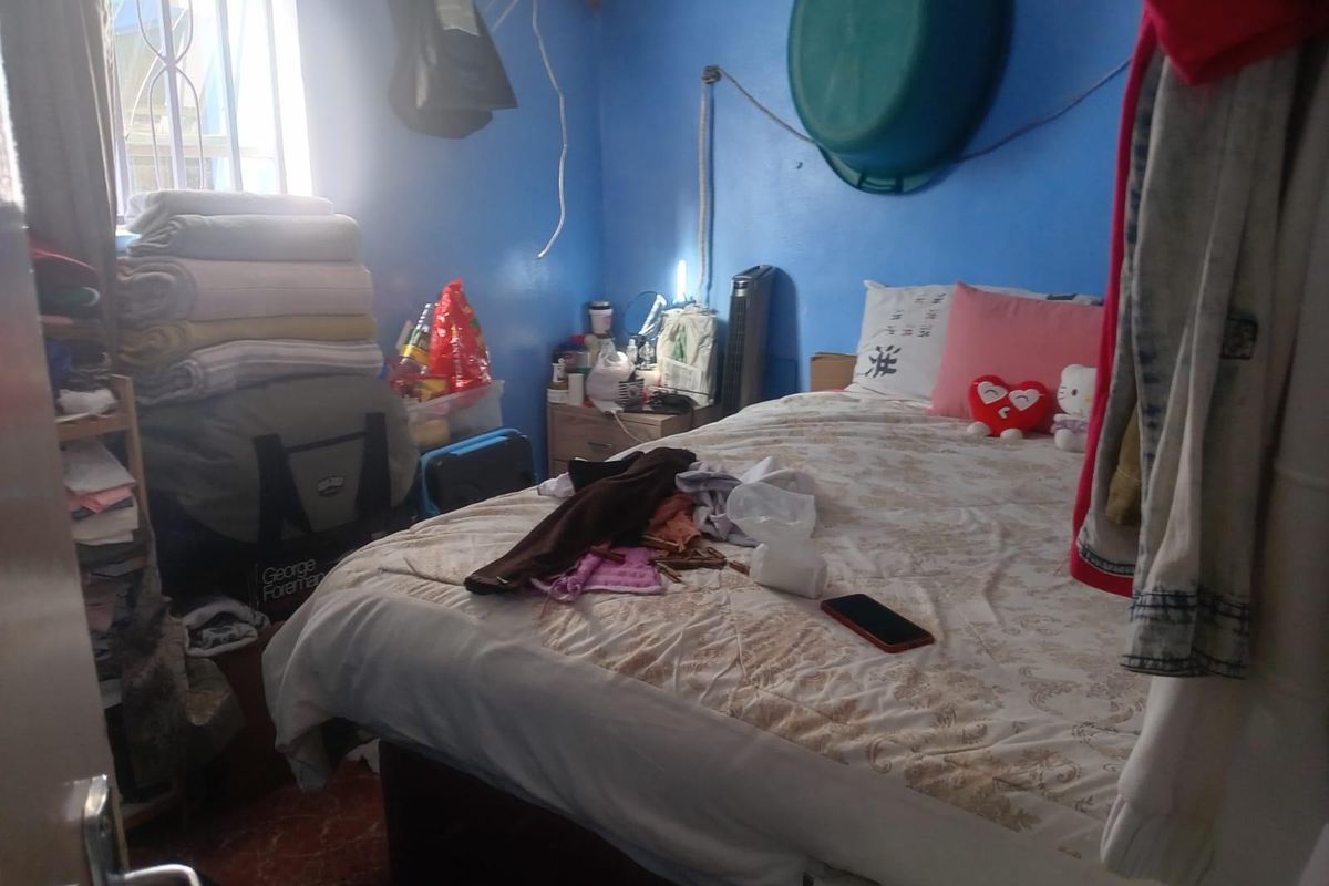 A bedroom featuring tiled flooring and security bars on the window, currently requiring maintenance to address exposed wiring and general upkeep.