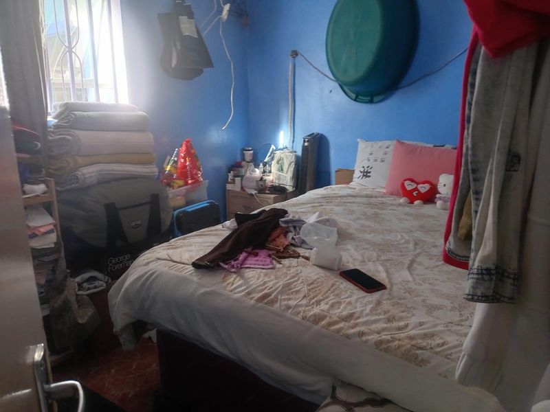 A bedroom featuring tiled flooring and security bars on the window, currently requiring maintenance to address exposed wiring and general upkeep.