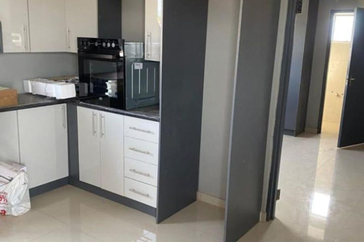 Modern kitchen featuring two-tone cabinetry, built-in oven, and polished floor tiles, offering a clean and functional space.