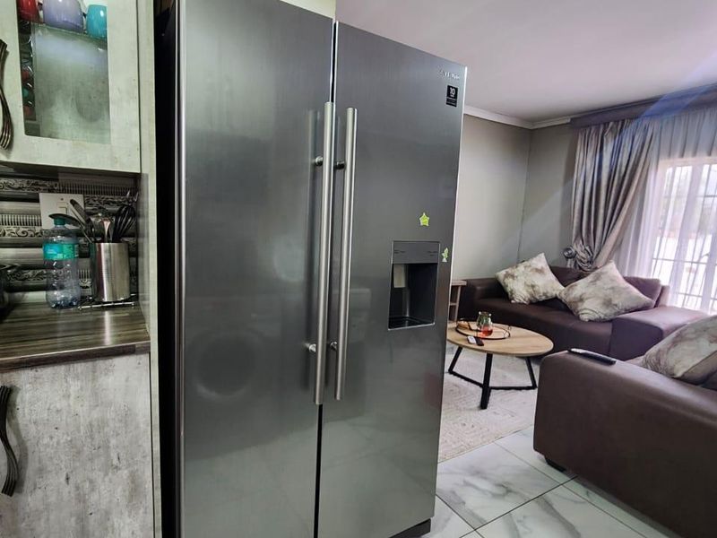 Open-plan living area featuring modern marble-look floor tiles and integrated kitchen cabinetry, seamlessly connecting the kitchen and lounge space.