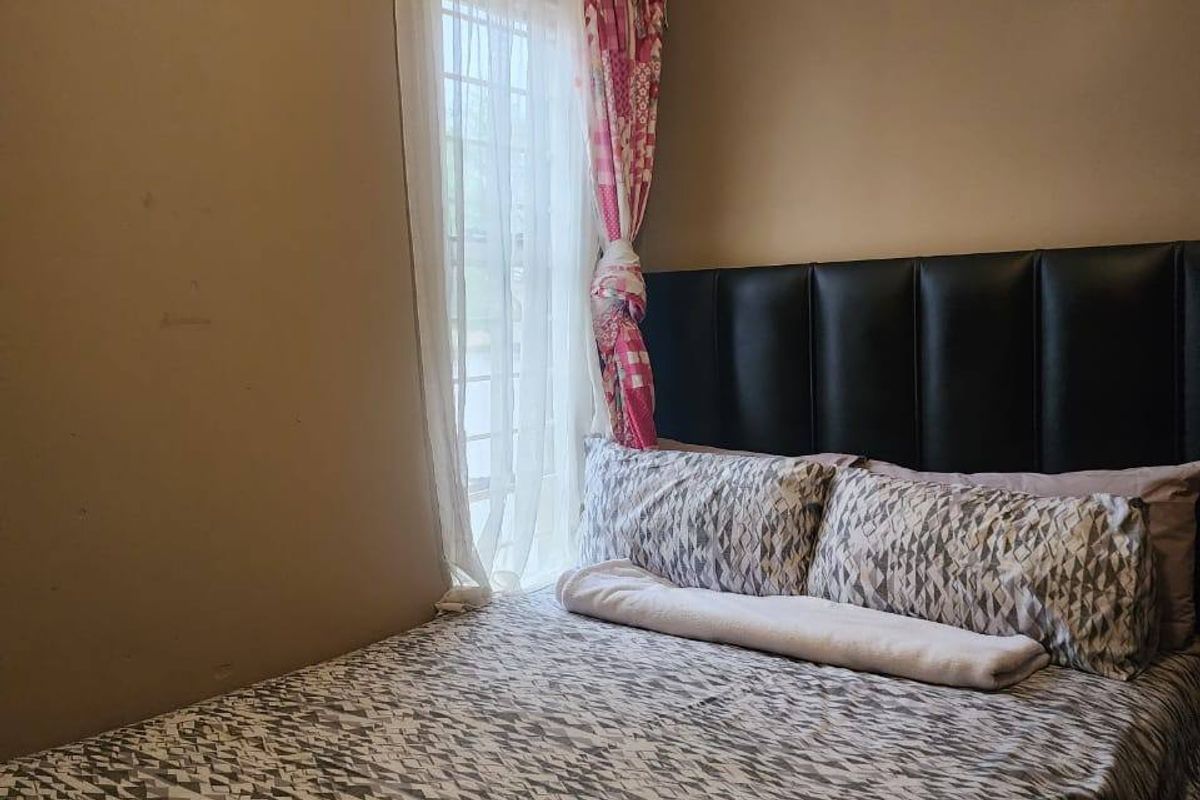 A standard bedroom featuring neutral wall finishes and a window with fitted curtain tracks.