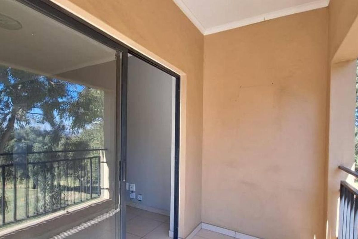 A covered balcony featuring tiled flooring, a metal balustrade, and a sliding glass door providing access to the interior living space.