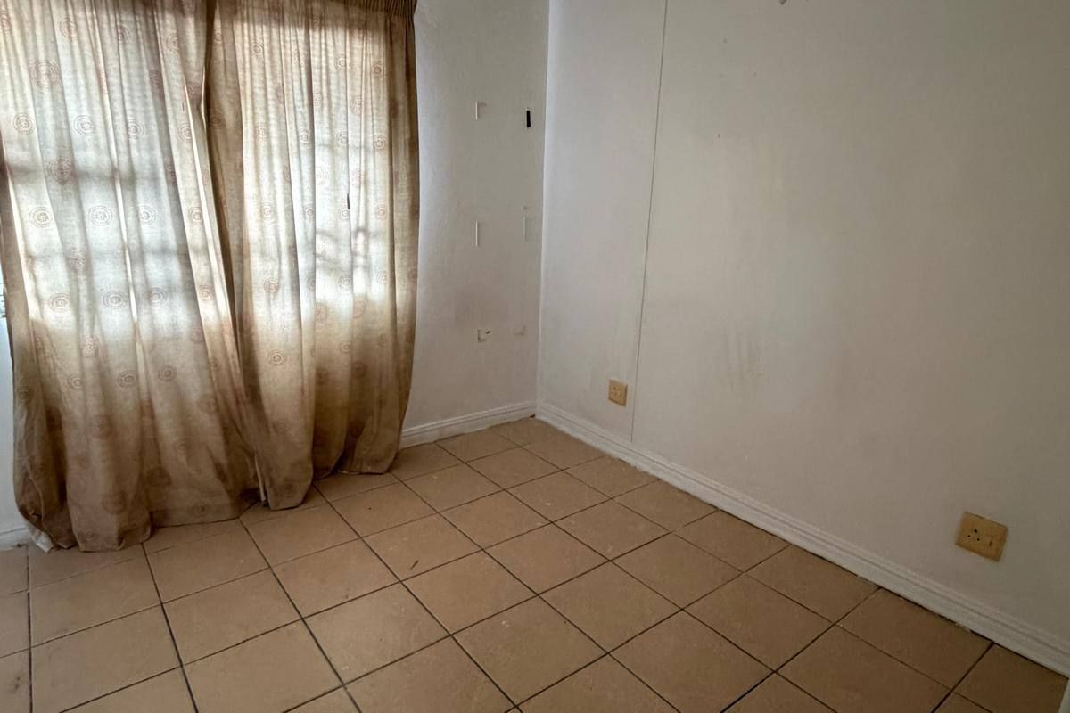 An empty bedroom featuring tiled flooring and neutral walls, ready for renovation or staging to enhance its appeal.