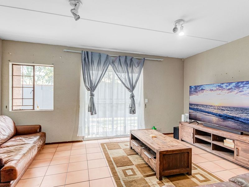 A living room featuring ceramic tile flooring, track lighting, and a sliding glass door providing access to the exterior.