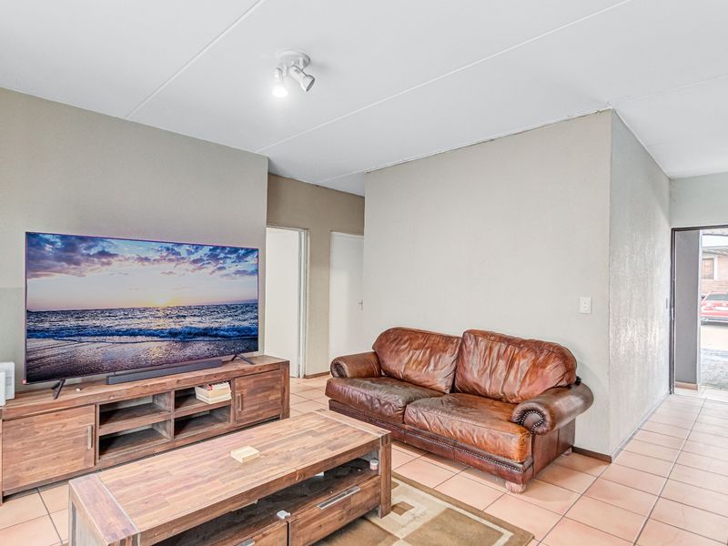 A living room area featuring tiled flooring and a ceiling-mounted spotlight fixture, providing a functional and neutral space.
