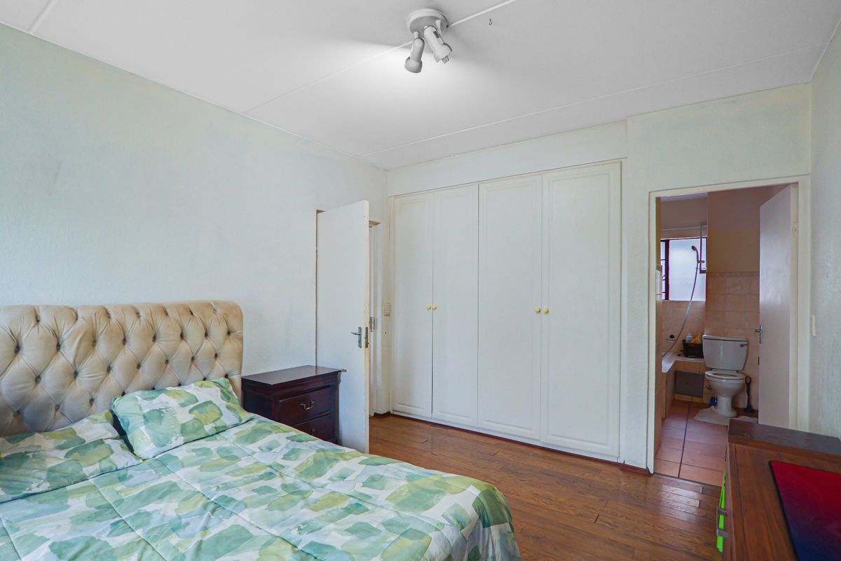 Bedroom featuring laminate flooring, built-in cupboards, and an en-suite bathroom access.