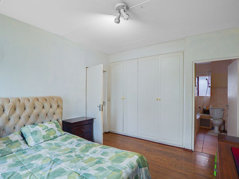 Bedroom featuring laminate flooring, built-in cupboards, and an en-suite bathroom access.