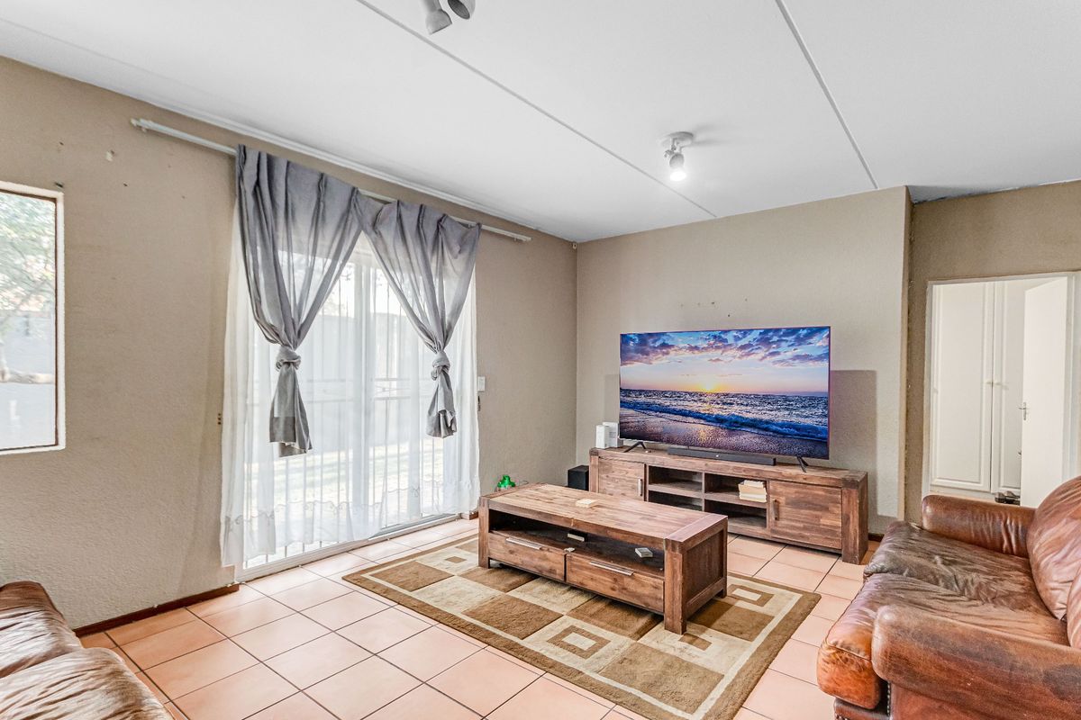 A living room featuring tiled flooring and a sliding glass door providing access to the exterior.