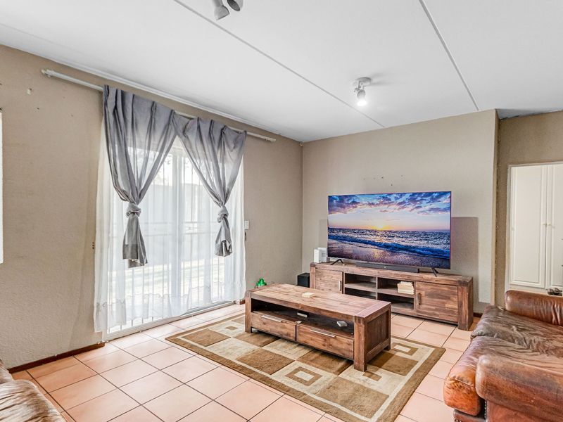 A living room featuring tiled flooring and a sliding glass door providing access to the exterior.