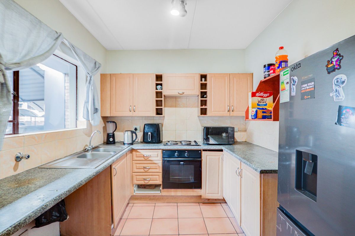 A functional kitchen featuring laminate cabinetry, granite countertops, a built-in oven, and tiled flooring, offering a practical layout for daily meal preparation.