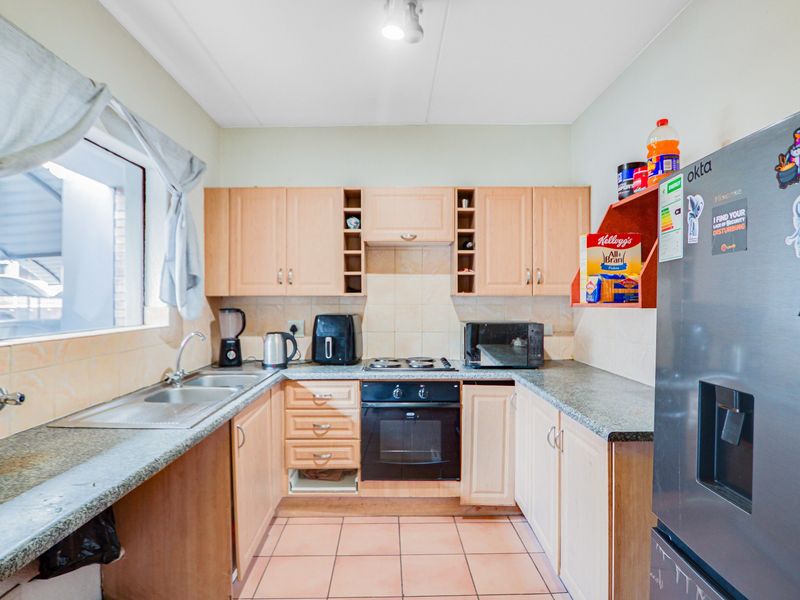 A functional kitchen featuring laminate cabinetry, granite countertops, a built-in oven, and tiled flooring, offering a practical layout for daily meal preparation.