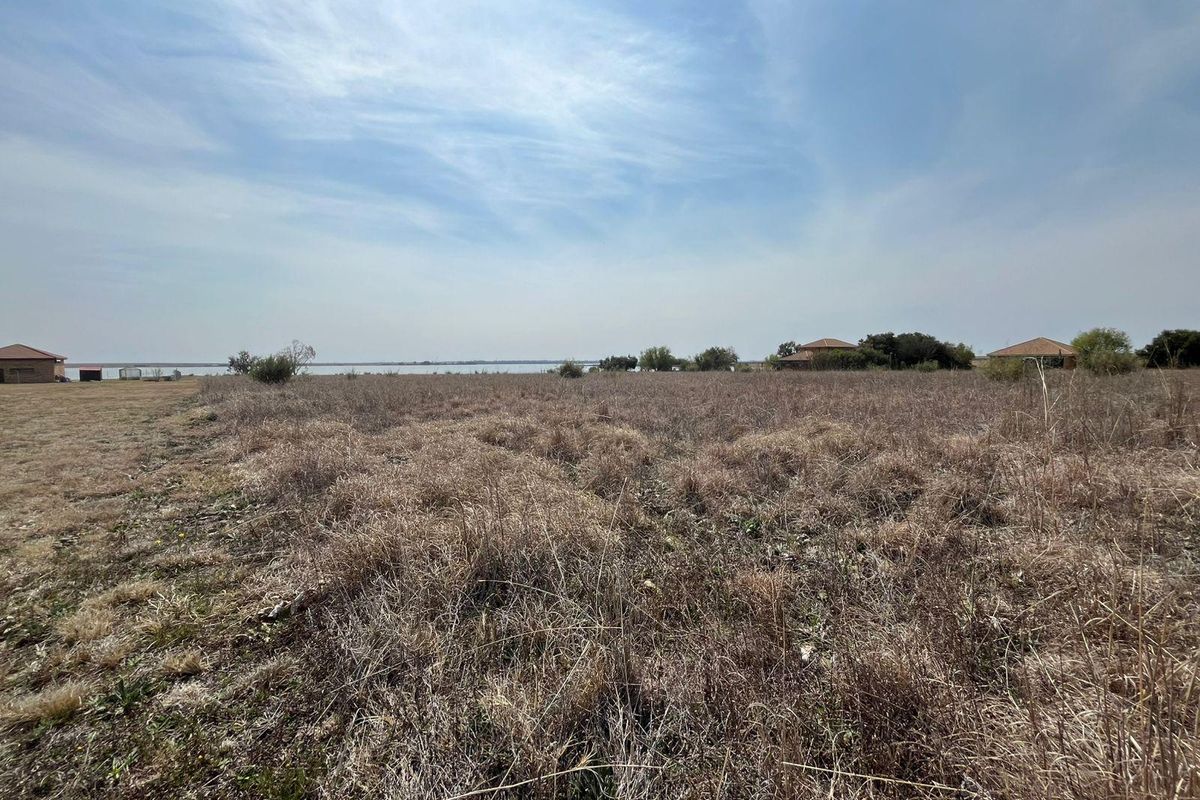 Expansive open farm land with scenic waterfront views and distant structures.