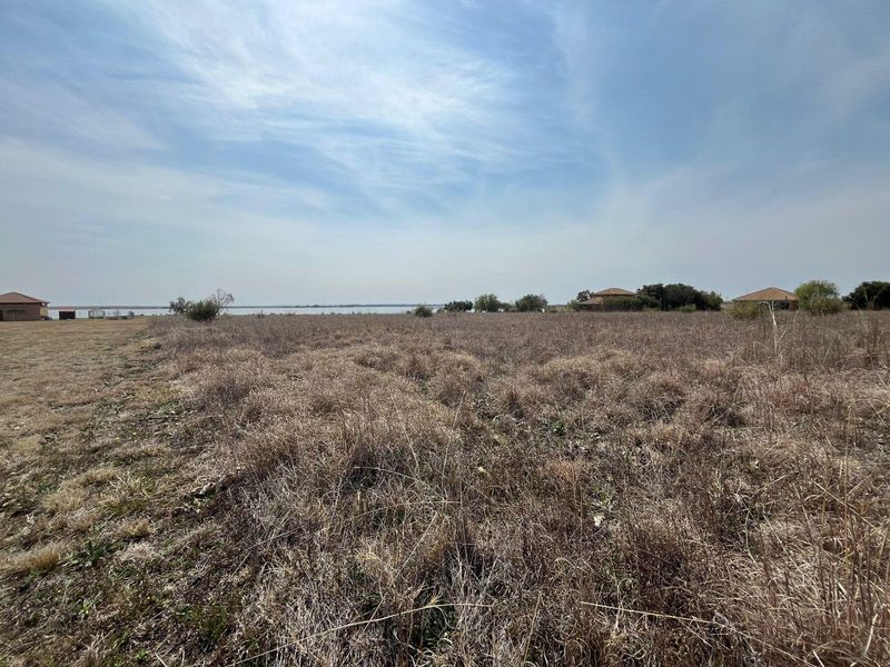 Expansive open farm land with scenic waterfront views and distant structures.