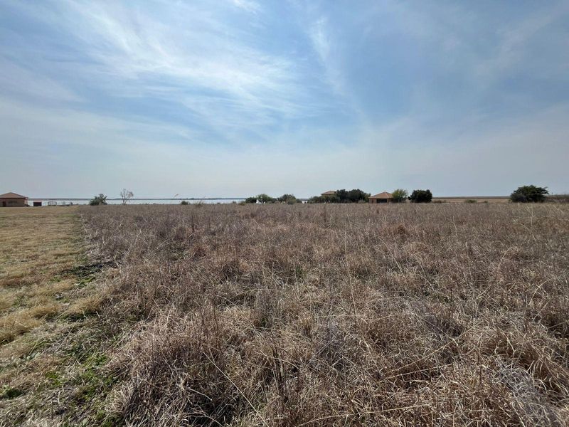 Expansive open field landscape with distant water views, showcasing the natural terrain and rural setting of the property.