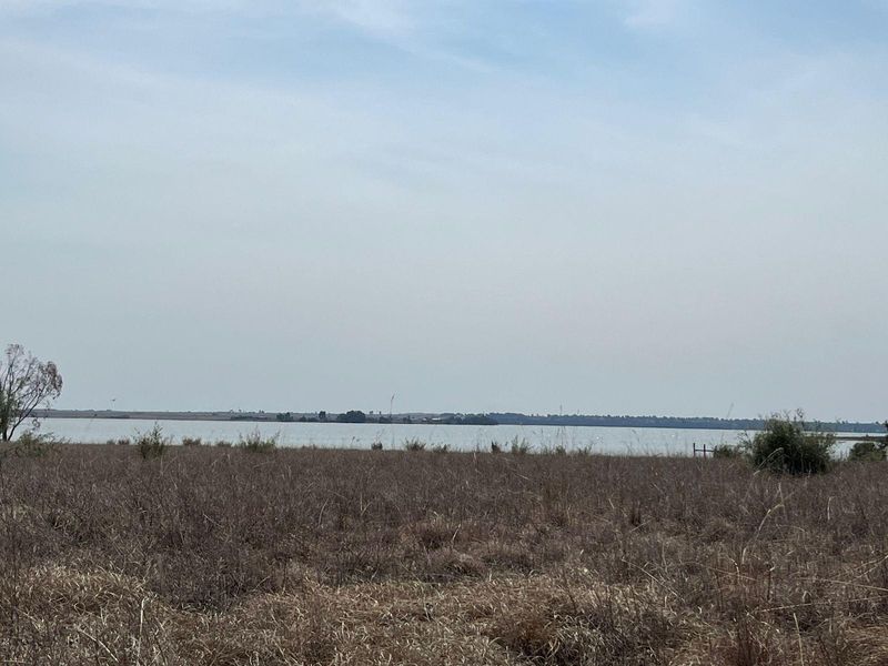 A scenic view of the open landscape and water body on the farm property.