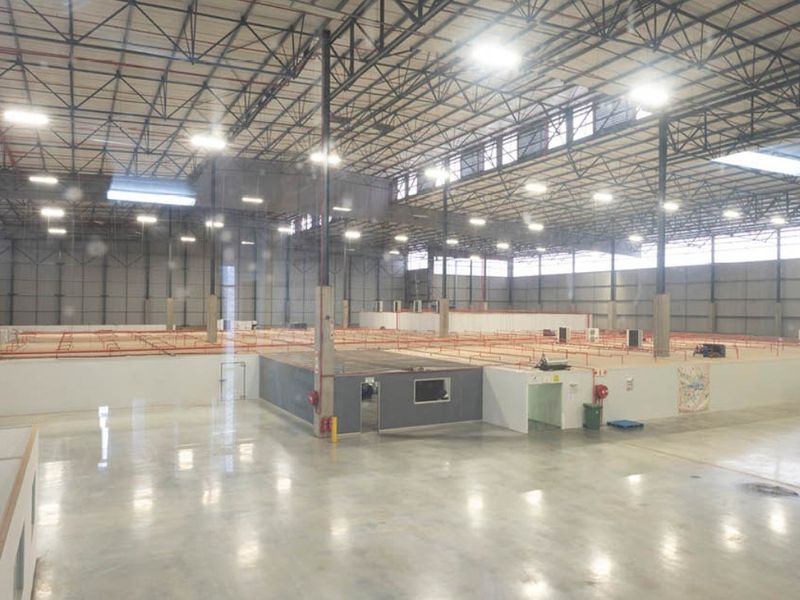 Expansive industrial warehouse space featuring high ceilings with exposed steel trusses, polished concrete floors, and integrated fire safety systems.