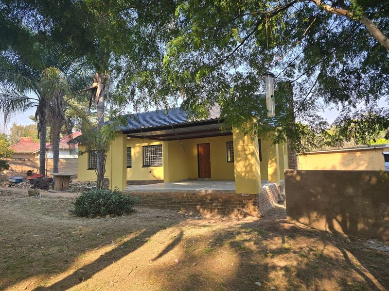 Rear view of the house featuring a covered patio area with brick foundation and security bars on the windows.