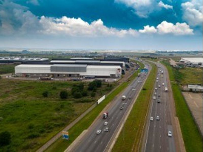 Aerial view of an industrial warehouse complex situated adjacent to a major highway, offering excellent logistical connectivity and visibility.