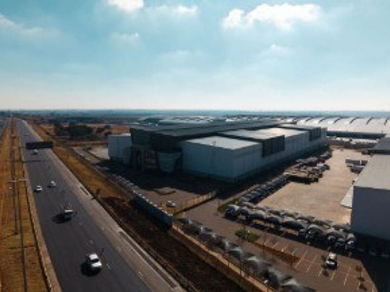 Aerial view of a large industrial warehouse facility featuring extensive parking areas and direct access to a major highway.